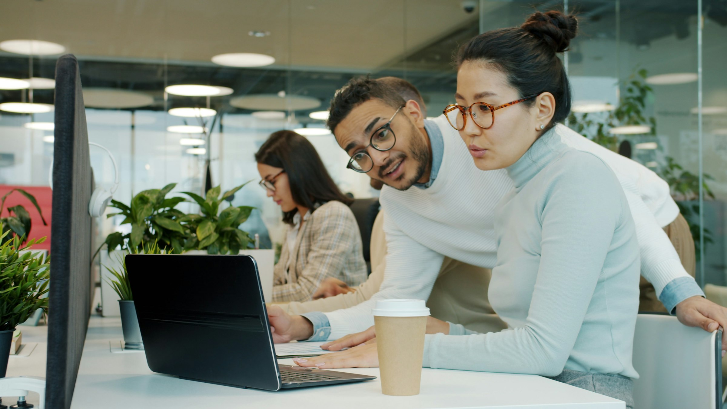 Two colleagues working through a question together at a laptop