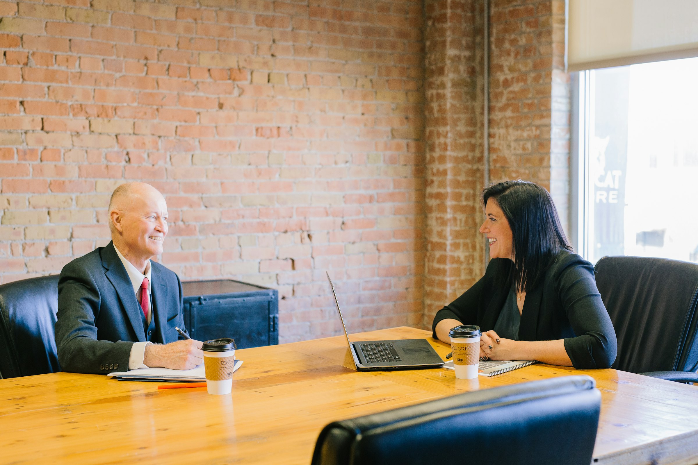 Two people talking across a meeting room table