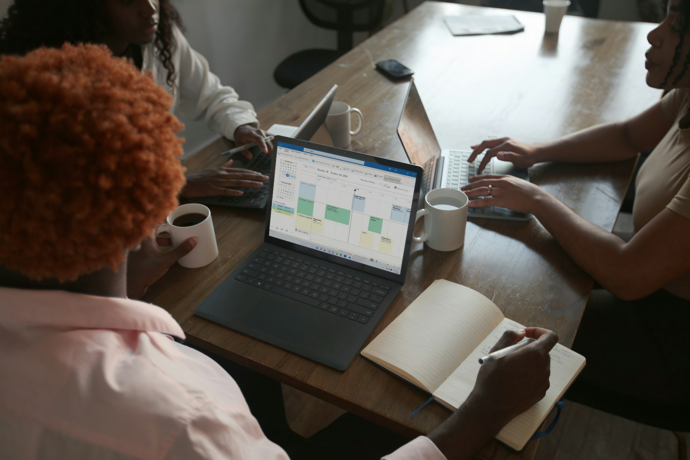 Three people discussing work around a laptop